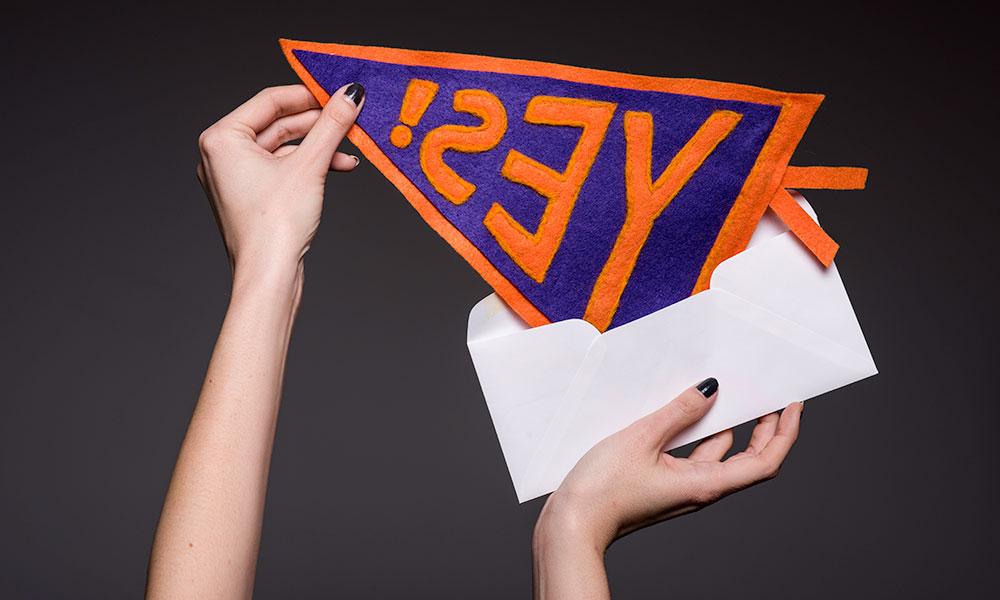 get into your dream college two hands pulling pennant out of an envelope. The pennant reads YES!