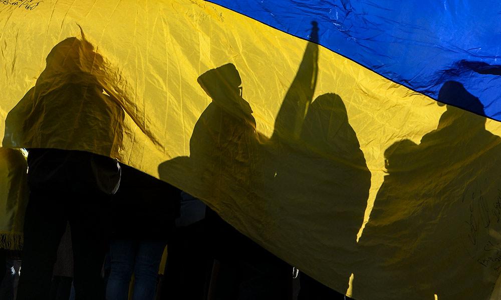 抗议者举着标语，透过一面乌克兰国旗.
