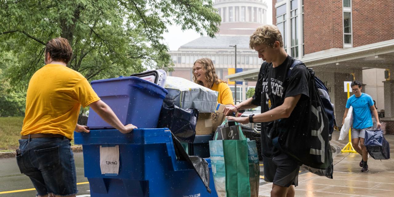 学生在入住当天用一个大的滚动垃圾箱搬运物品